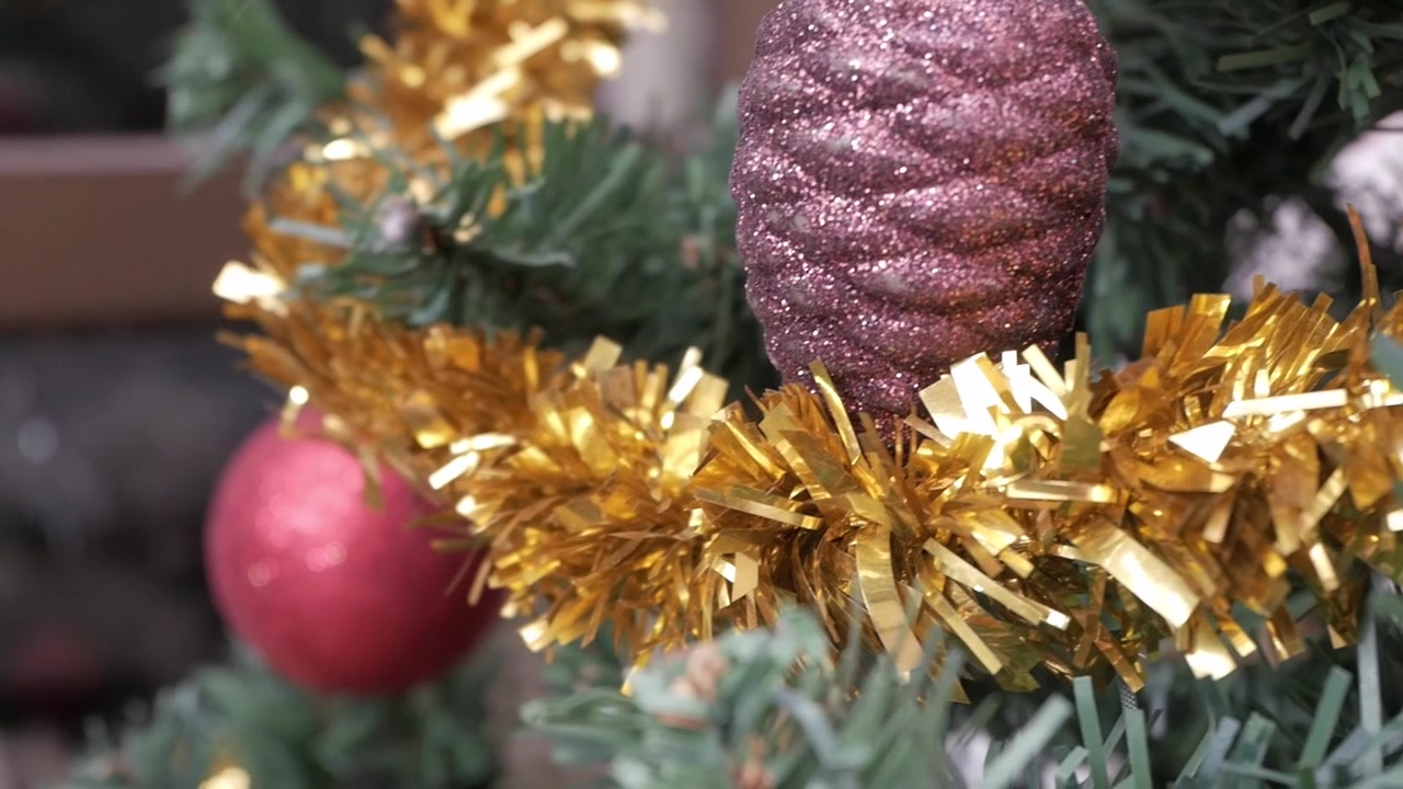 Festone dorato e decorazione a pigna scintillante su un albero di Natale ad Alicante, Spagna.