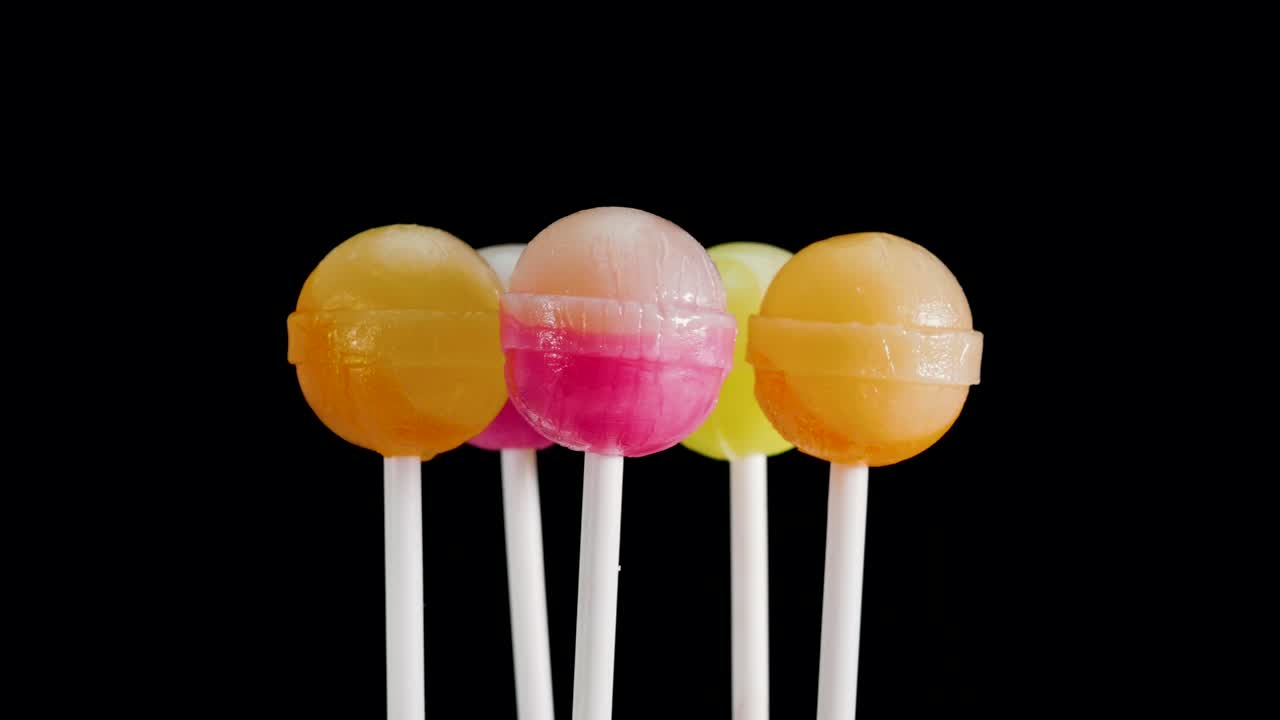 많은 다채로운 릴리이 검은 바탕에 회전하고 있습니다.  막대기에 달한 사탕