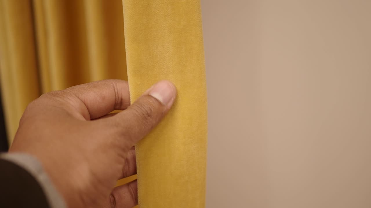 노란색 벨 커튼을 만지는 손