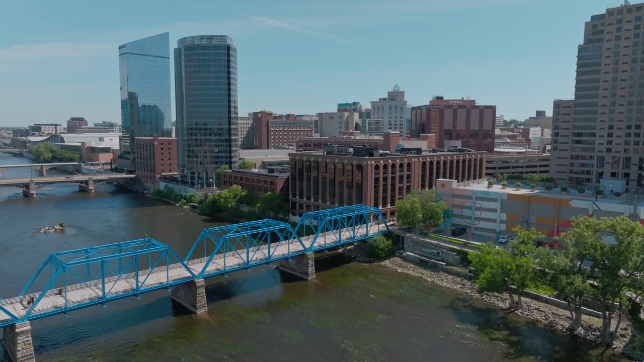 Blue bridges in Grand Rapids, Michigan over the Grand River with drone video moving up to see skyline