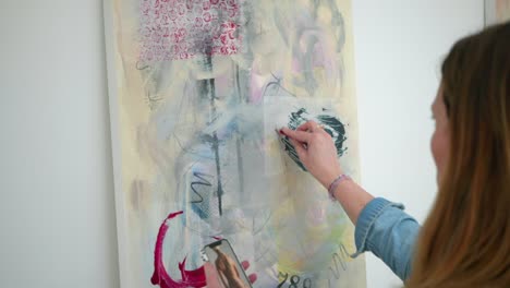 Female-artist-checks-composition-of-painting-on-canvas-with-fingers-and-pencil