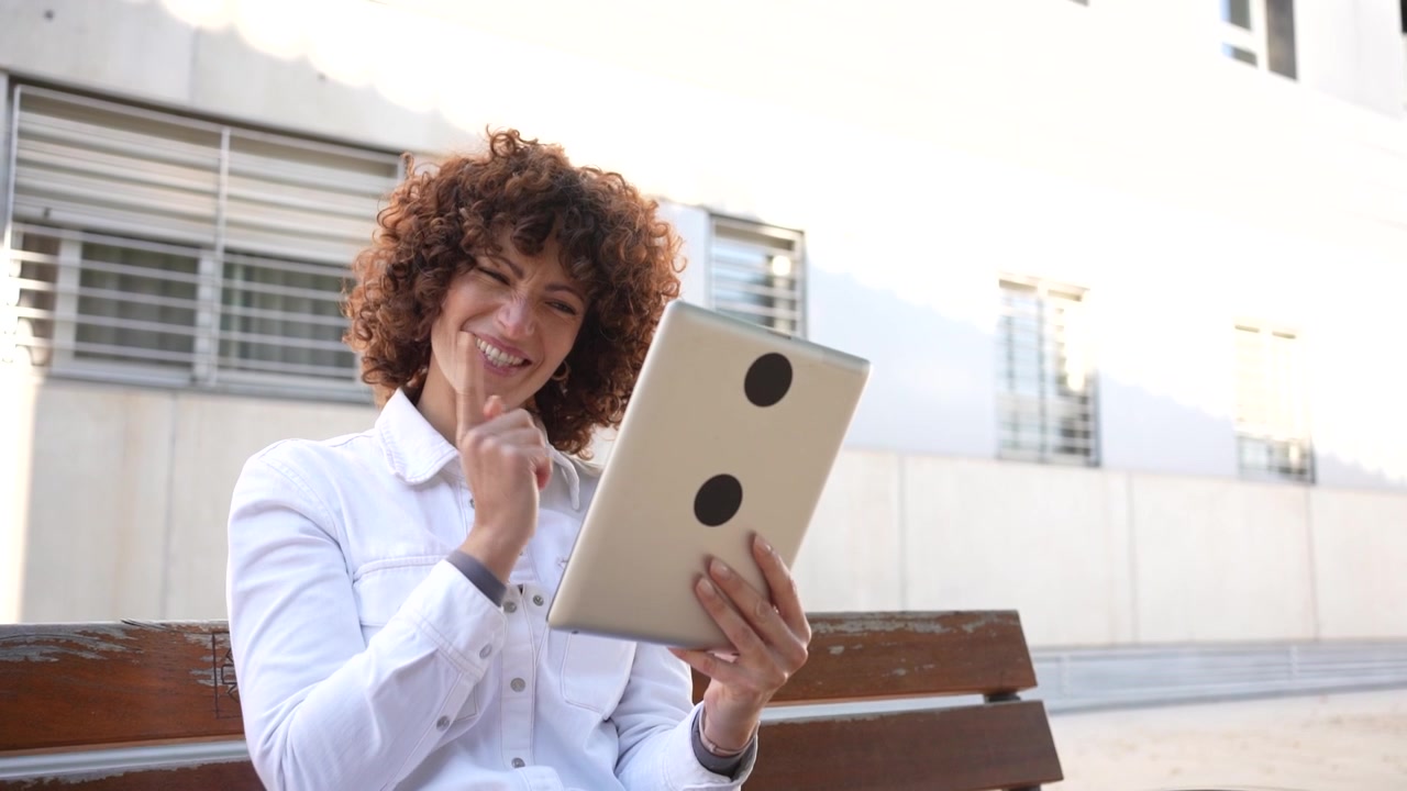 Uma mulher está usando seu tablet ao ar livre, situada em um ambiente contemporâneo e moderno.