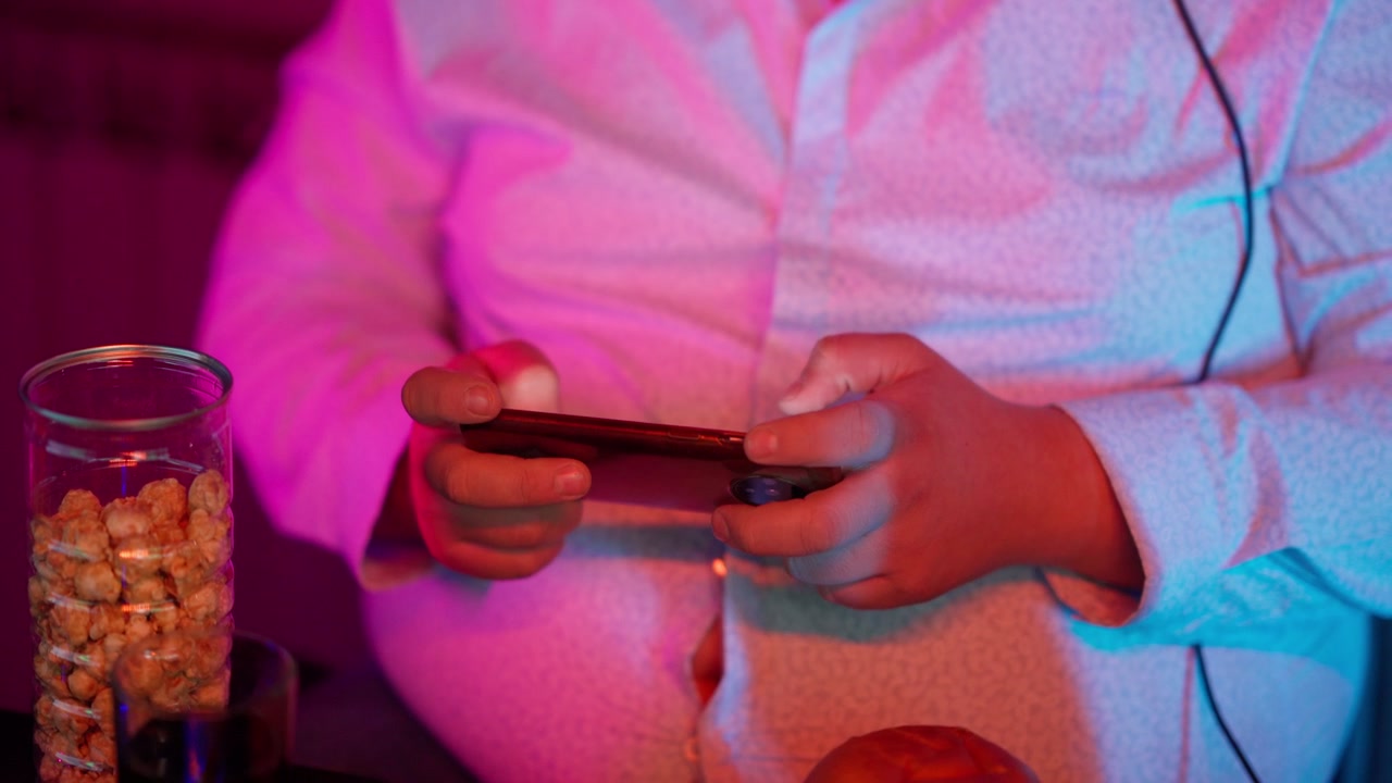 Primo piano di mani che giocano allo smartphone con illuminazione al neon