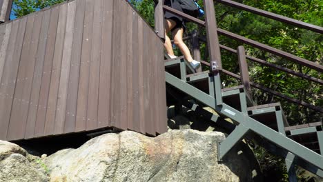 Chica-Rubia-Subiendo-Las-Escaleras-Con-Barandillas-En-Un-Día-Soleado-En-La-Montaña-Gwanaksan,-Seúl,-Corea-Del-Sur