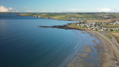 winter calm blue ocean and coastal sandy beach with small village in the distance, ireland, aerial