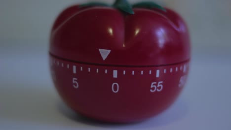 primer plano de un temporizador de cocción en forma de tomate que hace tictac hasta cero