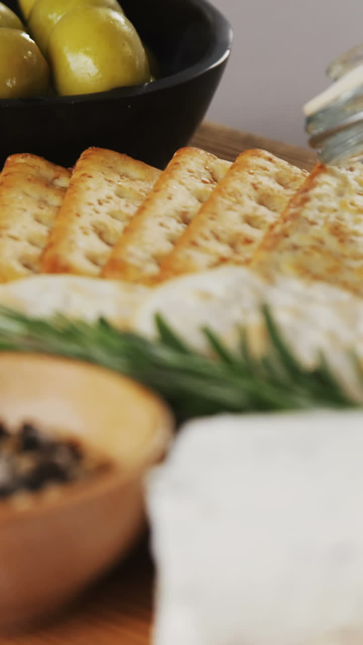 cuenco de aceitunas verdes, especias, galletas crujientes, mermelada, hierba de romero, queso y nueces