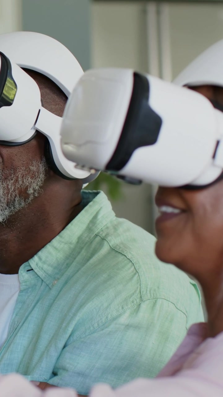Vertical video: Reacting to VR start, couple viewing virtual scene at home, wearing white headsets