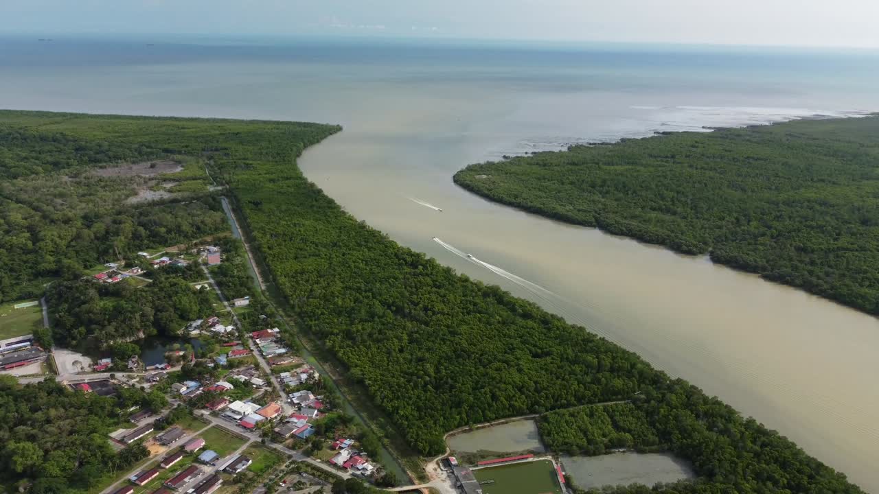 Drone shot of Parana River winding through dense green forest beside small riverside village in South America. Boats move across wide waterway leading toward vast blue horizon and open sea.
