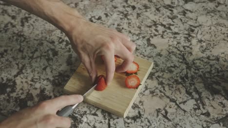 mano de una persona cortando frutas frescas de fresa