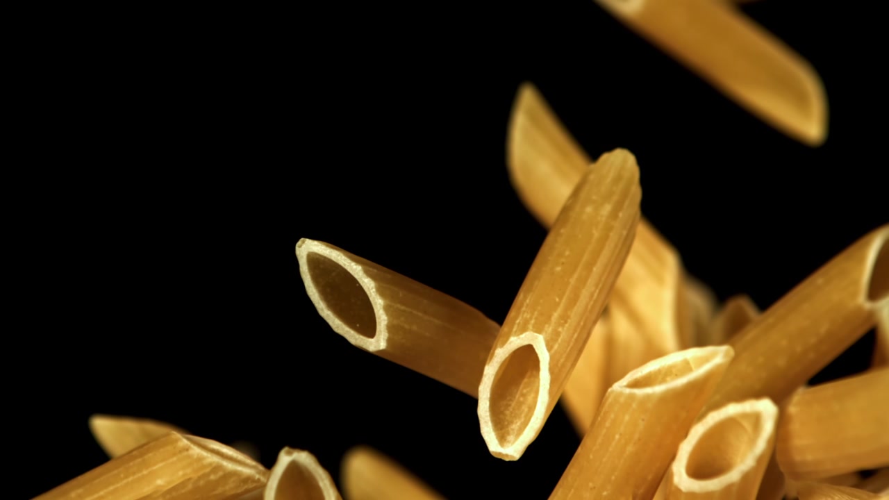 Penne secche che cadono al rallentatore su sfondo nero