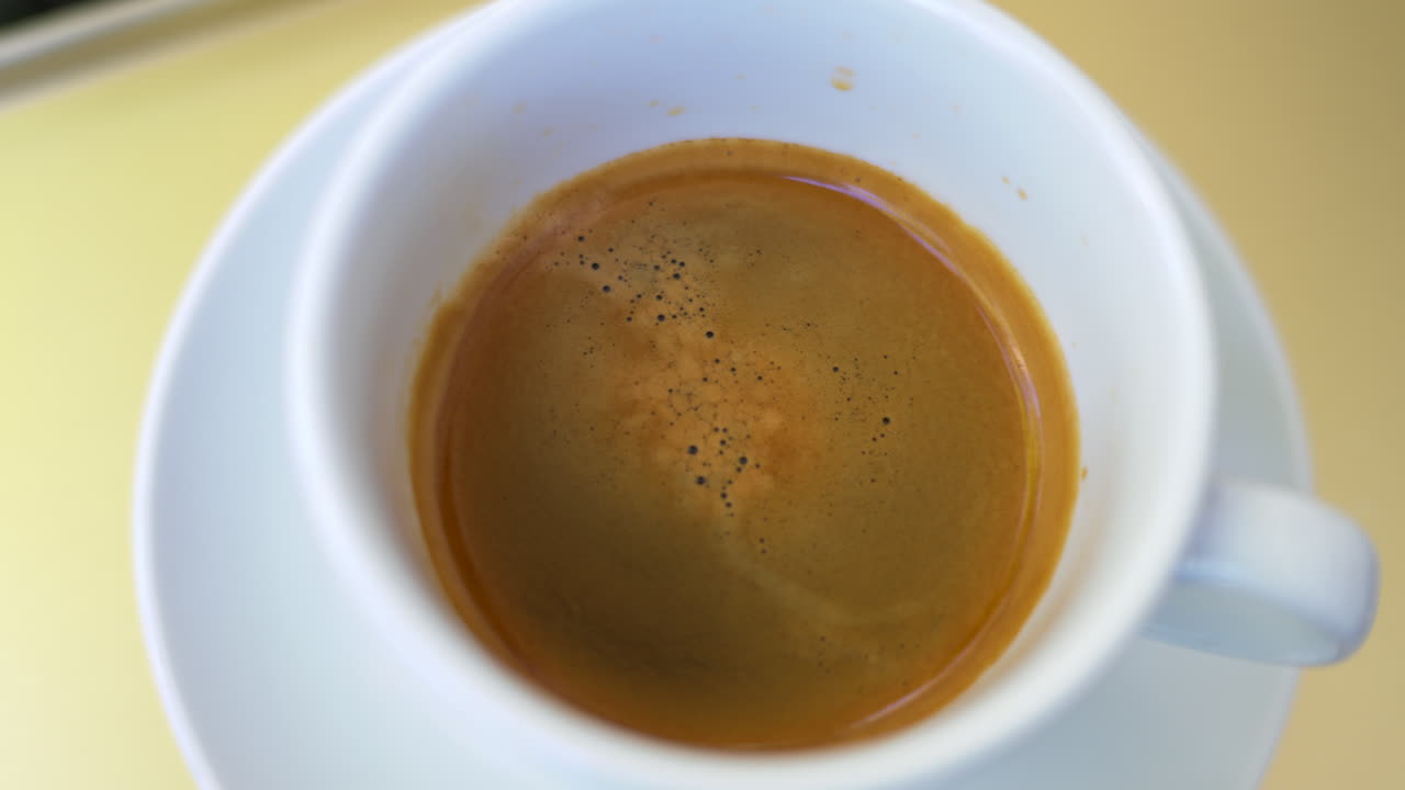 Cup of black coffee close up, slow motion top view