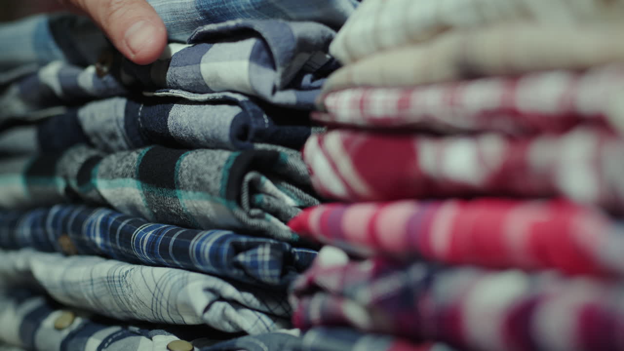 las manos de los hombres clasifican la ropa en una pila en el estante