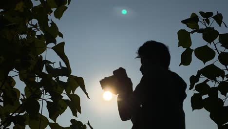 closeup shot of young man taking photographs with dslr camera, silhouetted