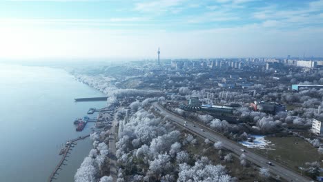 Vista-Aérea-Del-Río-Danubio,-Automóviles-Circulando-Por-La-Carretera-Con-La-Torre-De-Televisión-Galati-En-La-Distancia-En-Invierno-En-Galati,-Rumania