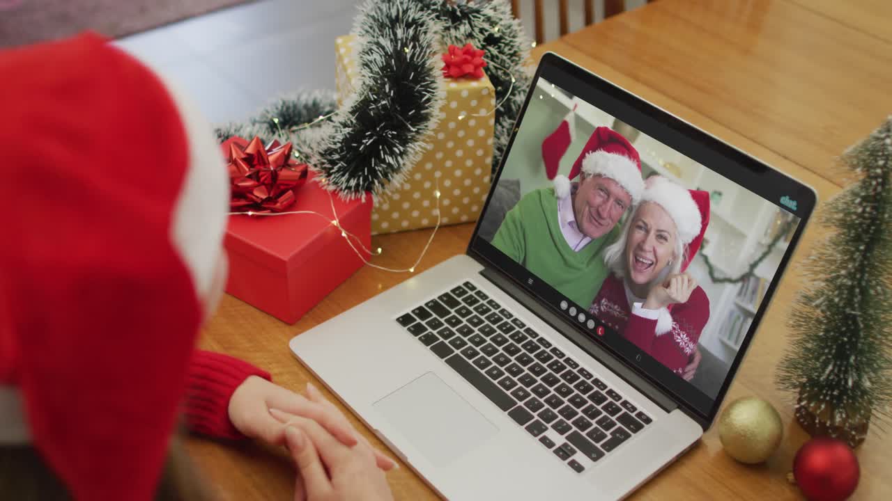 mujer caucásica en videollamada en computadora portátil con los abuelos en tiempo de navidad