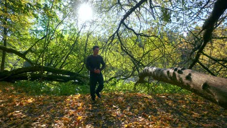 un hombre haciendo una exhibición de salto sobre el tronco de un árbol durante la temporada de otoño en lituania- tiro de seguimiento