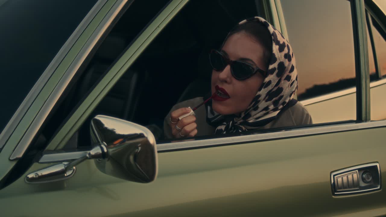 Donna che si mette il rossetto in un'auto d'epoca