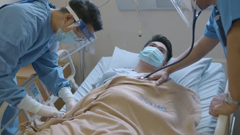 hospital doctor and nurse checking the male patient's heartbeat and blood tube