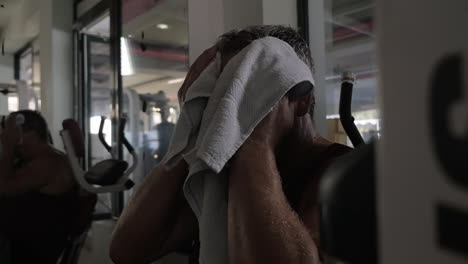 tired man wiping sweat after workout in the gym