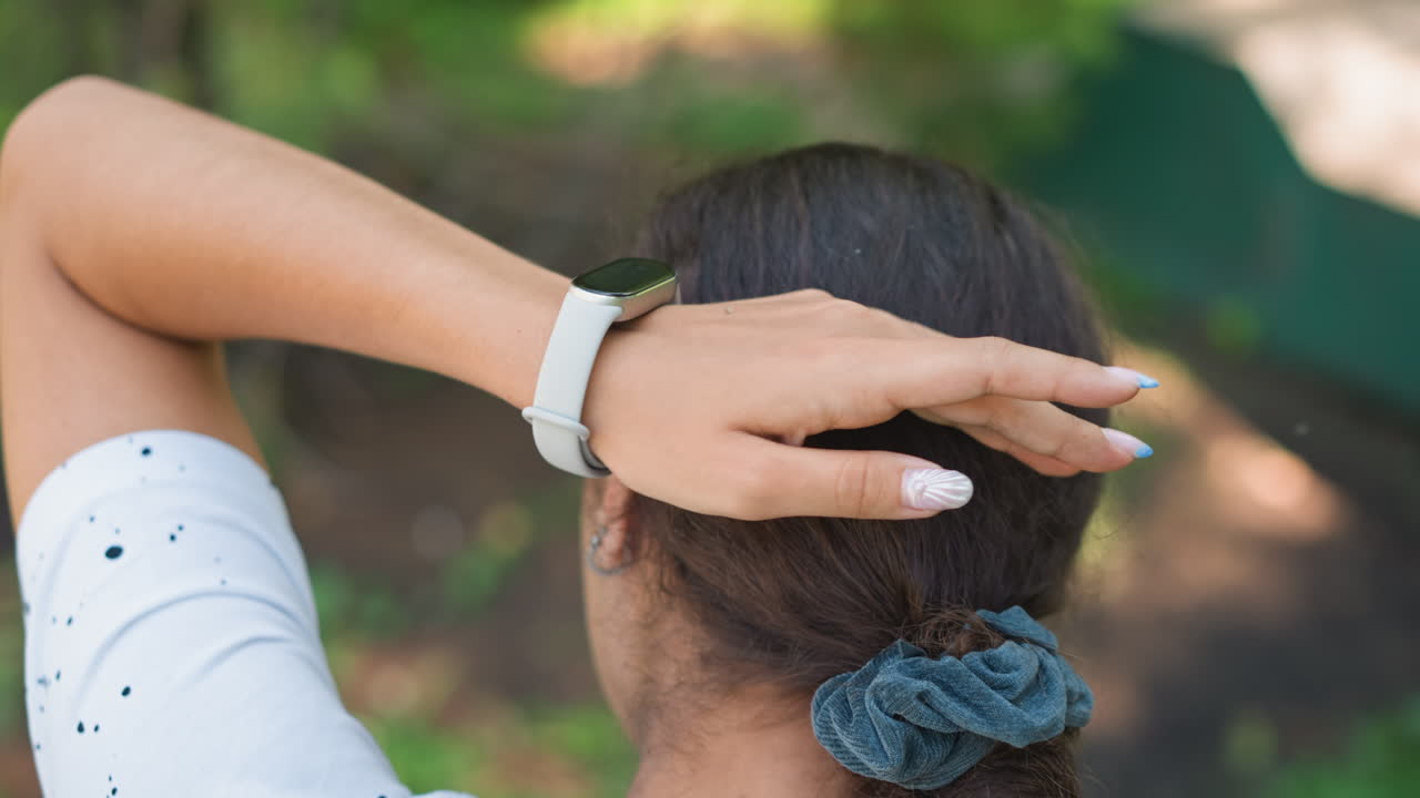 Forest woman resting, Young female hiker reflects while adjusting bun in forest sunlight, Serene scene of woman hiking through trees as she rearranges her hair in peaceful surroundings