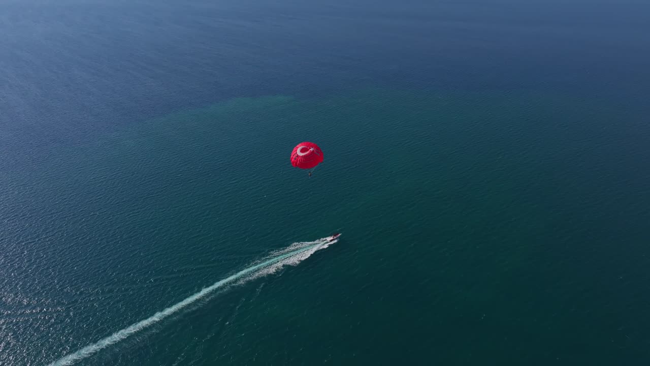 Overhead view of parasail above island chain and mountain coast