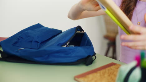 primer plano de las manos de una niña sacando libros de su mochila escolar