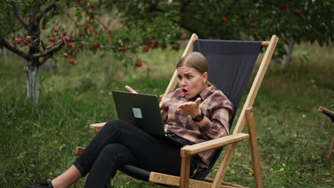 troubles and hardships in freelance remote work. lady looks puzzled and surprised with something working on laptop outdoors remotely from office.