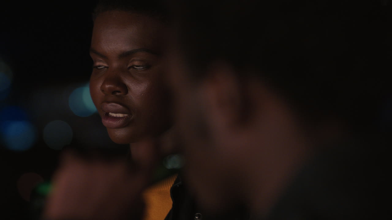 молодые друзья проводят время на крыше ночью, общаются, разговаривают, наслаждаются городским вечером, афроамериканский мужчина флиртует с красивой женщиной на свидании.