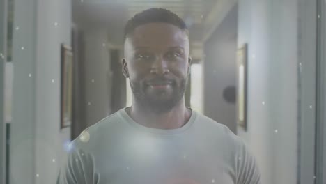 animatie van glimlachende afro-amerikaanse man thuis over witte vlekken