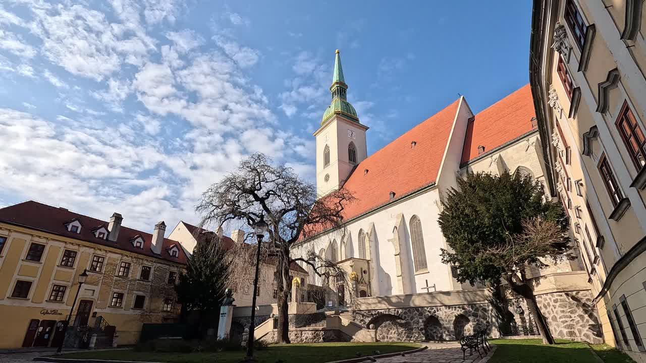 St. Martin's Cathedral with historic buildings and bare trees under a bright sky in Bratislava Old Town, Slovakia