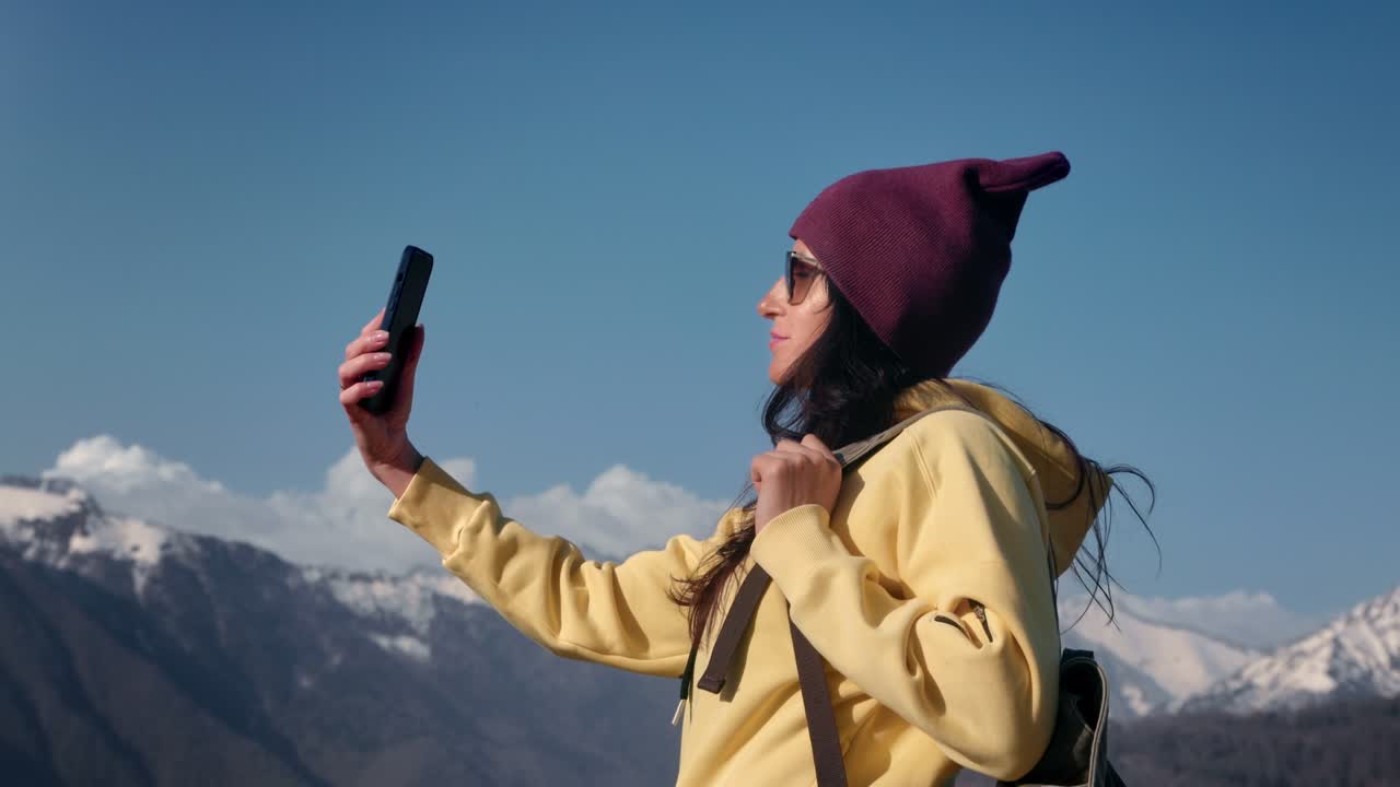 Smiling backpacker travel woman posing taking selfie smartphone at mountain snow peak sky landscape