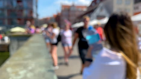 out of focus shot of people walking on bridge in city during sunny day