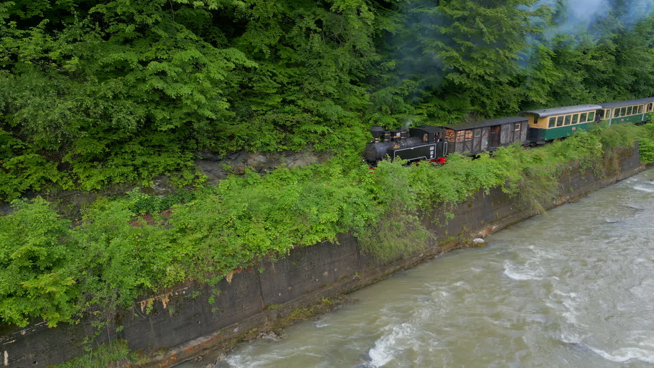 Fantastic aerial view of Mocanita steam train running along Vaser river in Maramure Mountains