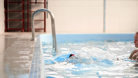 baby in the pool jumping from the side into the water and swims to his mother in slow motion