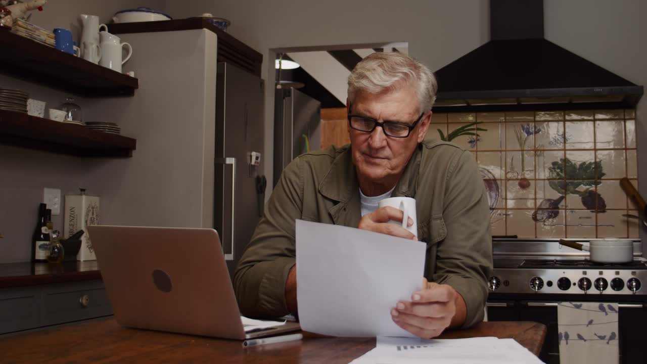 hombre caucásico de edad avanzada trabajando desde casa bebiendo café