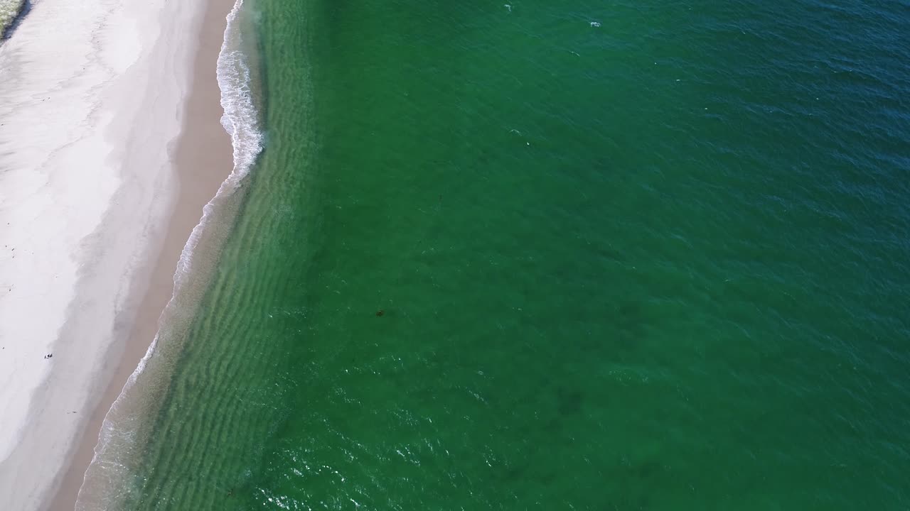 rotación lenta mirando hacia abajo sobre olas tranquilas con aves marinas blancas y agua esmeralda