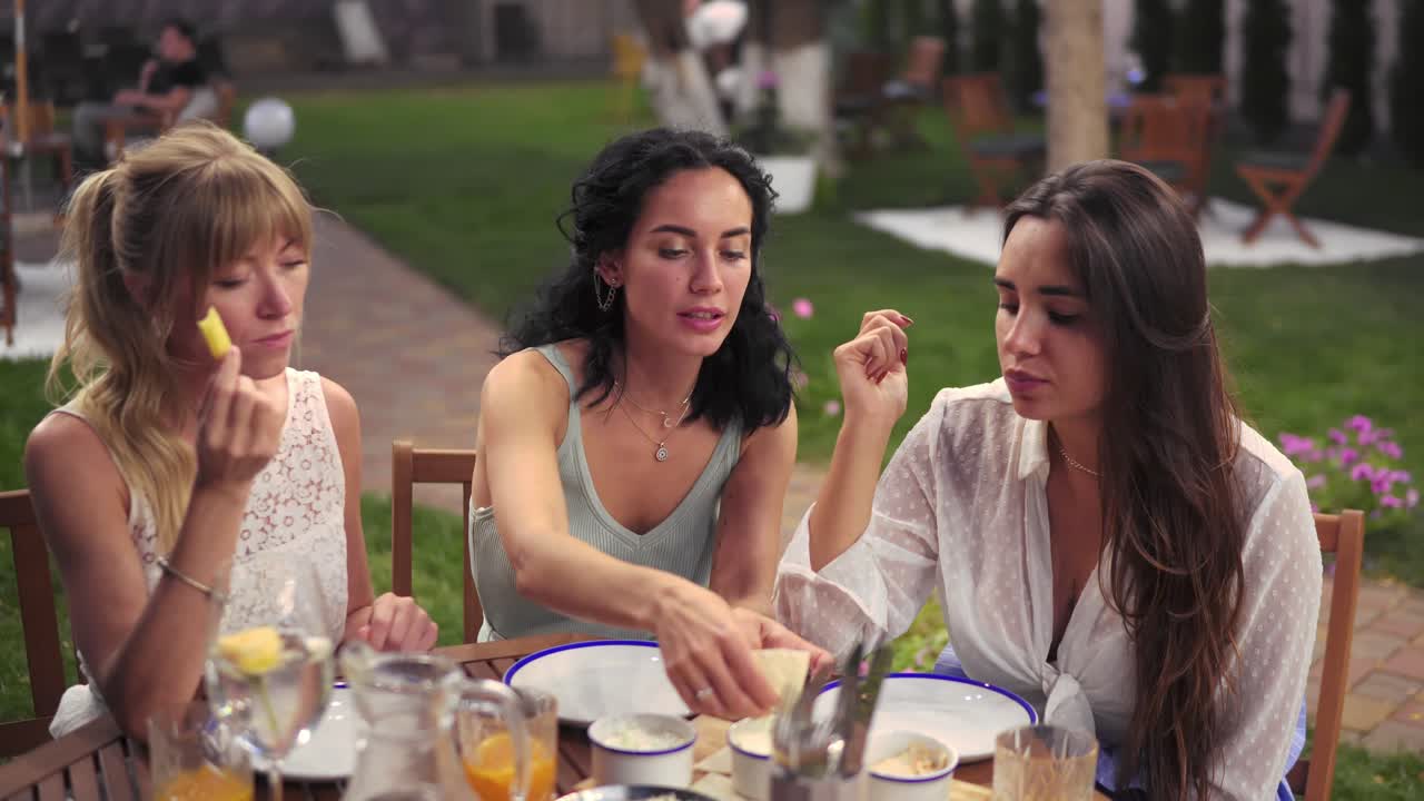 tres mujeres alegres descansando hablando bebiendo, tomando en el verano veranda café casual ciudad modelos de amistad al aire libre