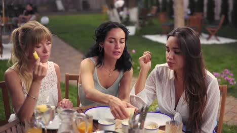 three cheerful women resting talking drinking, taking in summer veranda cafe casual city friendship models outdoors