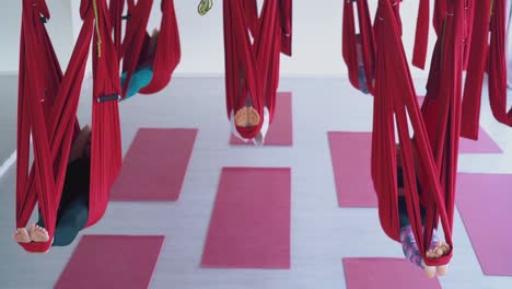 las damas disfrutan acostándose en hamacas de yoga de mosca roja restaurando la energía
