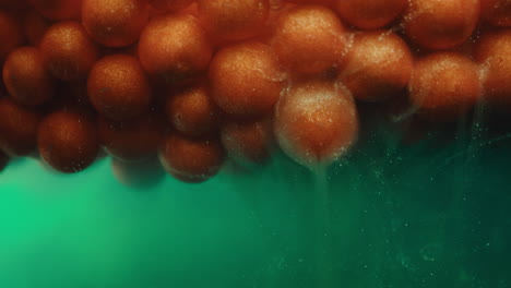 close-up of orange spheres in green liquid