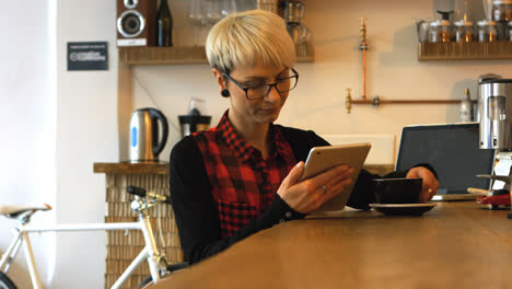 female business executive using digital tablet while having coffee