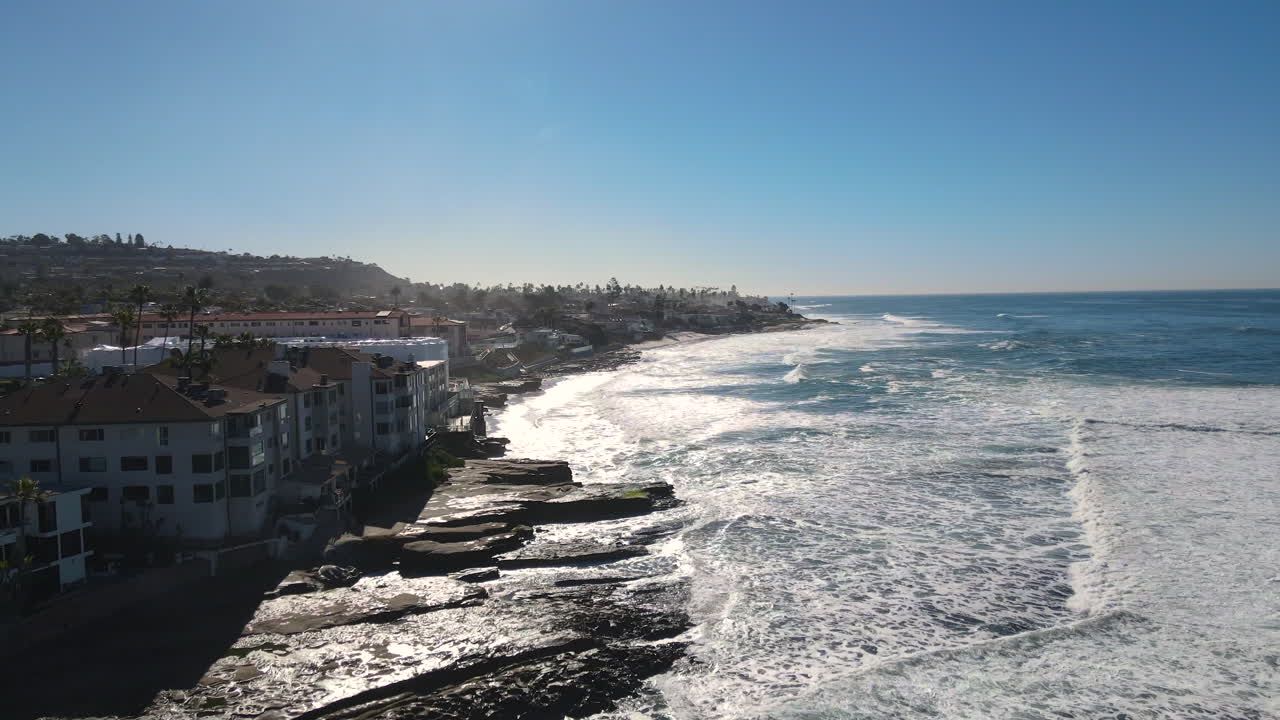 Stunning Coastal View of Ocean Waves Crashing on Rocky Shore with Houses