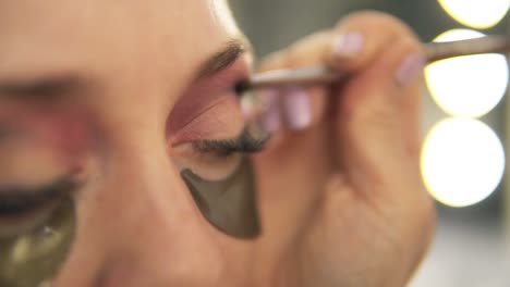 make-up artist applying eye shadow to model's eye. close up view. patches