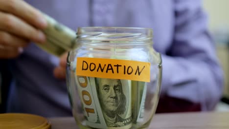 caucasian man putting a glass jar put in a drawer table with his savings for donation