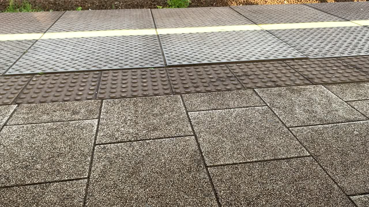 Slow motion low angle shot of woman with high heels walking along track at train station