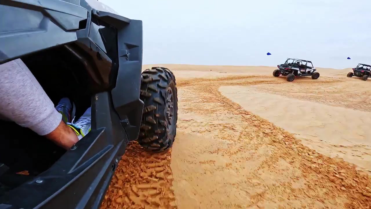 Prospettiva dinamica da un buggy che attraversa le dune del deserto di Dubai, con solchi di sabbia.