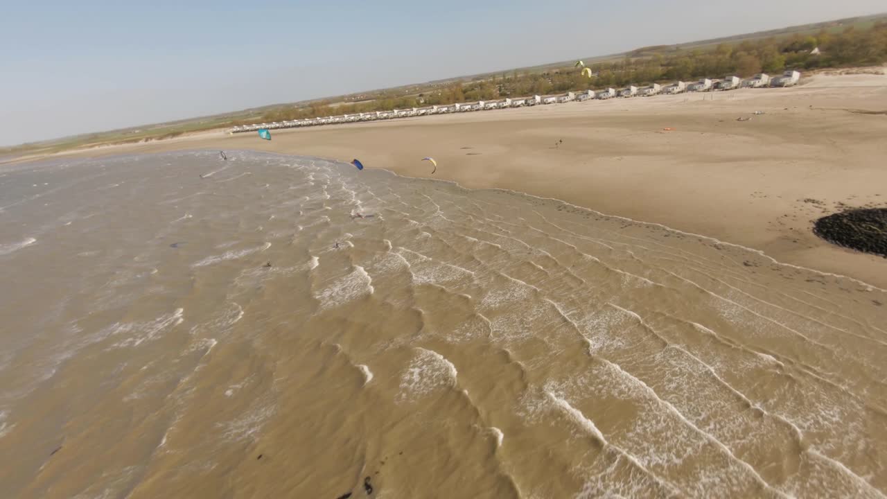Aerial drone flight over group of kite surfers in rough waves and strong wind
