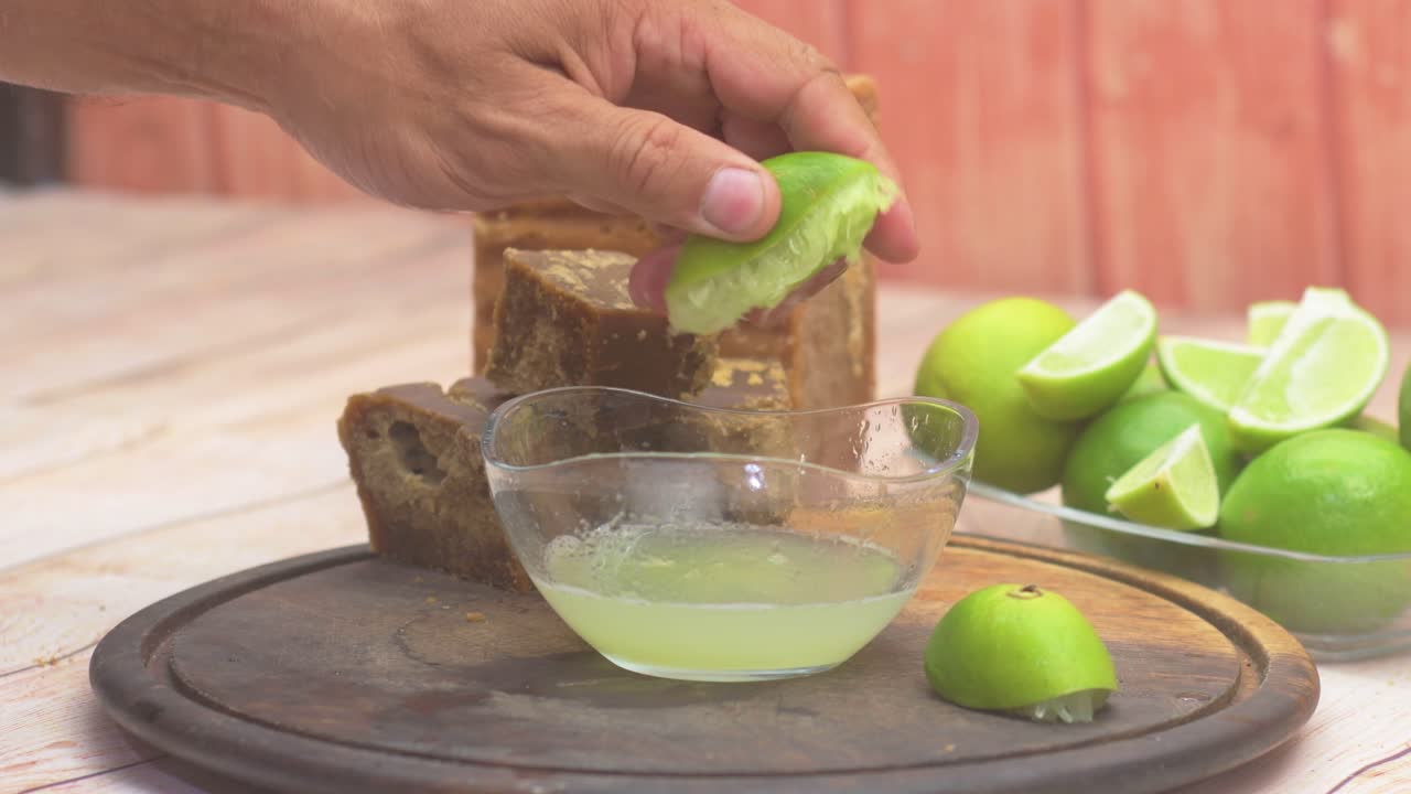 Hands Squeezing Fresh Lime Juice over Panela Sugar Block