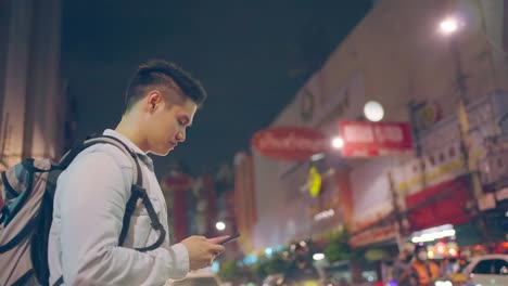 close up of asian man backpacker chatting on mobile phone walk in city. active handsome man tourist traveler travel alone on street use smartphone enjoy spend time on holiday vacation trip in thailand